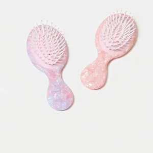 Primo piano di mini spazzole per capelli marmorizzate rosa e blu per la cura dei capelli.