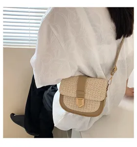 Stylische Stroh-Satteltasche mit braunem Lederbesatz und Goldschnalle am Modell gezeigt