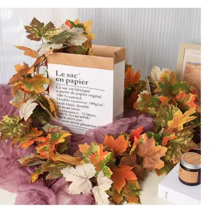 Close-up detail of realistic artificial autumn maple leaf garland with warm rustic props