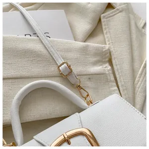 Detailaufnahme einer weißen Handtasche aus genarbtem Leder mit goldenen Schnallen