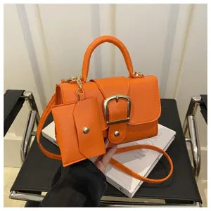 Makroansicht einer leuchtend orangen kleinen Tasche mit goldener Schnalle