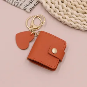 Orange mini leather photo keychain detail showing cute heart pendant and gold hardware rings.