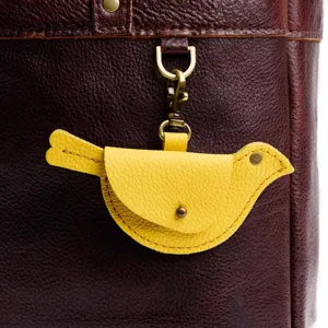 Close-up of yellow leather bird coin purse charm, detailed stitching and bronze hardware.