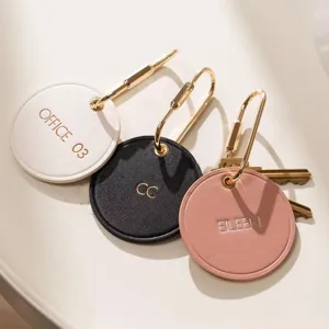 Porte-clés rond minimaliste en cuir avec fermoir en laiton et étiquette gravée personnalisée.