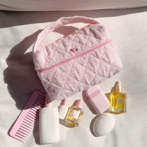 Pink quilted towel cosmetic bag detail shot, soft plush makeup pouch with zipper and rose embroidery.