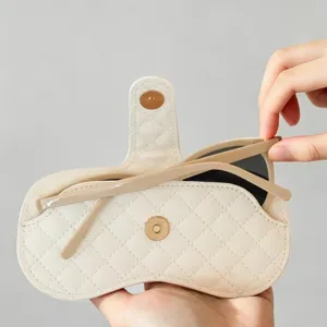 Detailed view of white quilted leather glasses case with diamond pattern and snap closure.