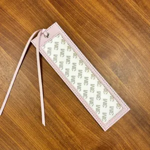 Pink PU leather cross-stitch bookmark sleeve with clear window and self adhesive backing.