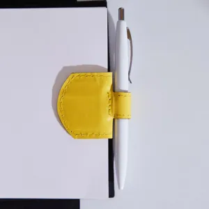 Detail shot of the yellow leather magnetic pen clip and bookmark holding a white pen securely.