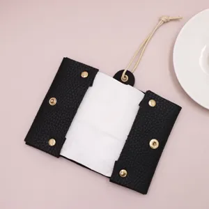 Primer plano de funda de pañuelos mini de cuero PU negro con broches dorados y cordón colgar.