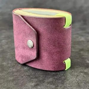 Leather wrap wallet detail shot, maroon pouch with magnetic snap and bright green elastic bands.