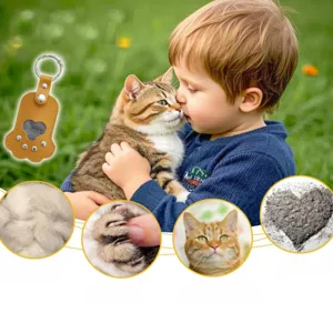 Detail view of cat claw pet keepsake keychain with hair and ash storage window in green grass.