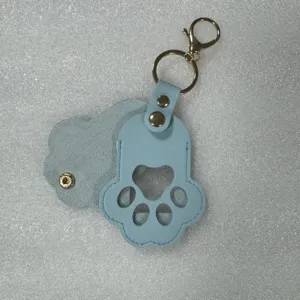 Close up of cute pet paw leather keychain detail in blue PU material with secure snap button.