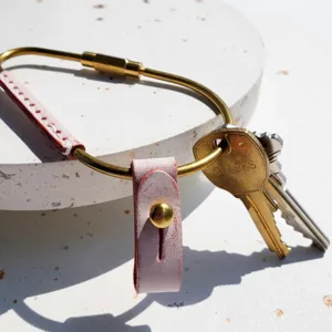 Brass carabiner keychain with pink leather wrap and rivet detail, perfect for car keys.