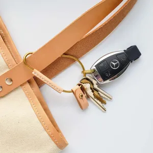 Close-up detail shot of PU leather brass carabiner keychain with retro rivet and car key pendant.