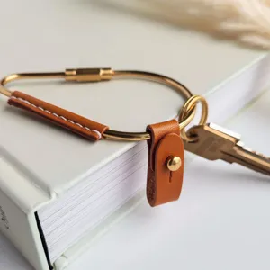 Close-up detail of brass metal loop keyring with brown PU leather wrap and snap button.