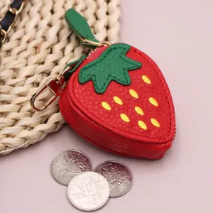Primo piano di un grazioso portamonete a fragola rossa in pelle PU con foglie verdi e gancio.