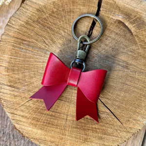 Close-up detail of a stylish red PU leather bow keychain with antique bronze metal ring hardware.