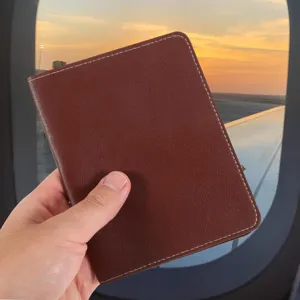 Close-up detail of brown PU leather passport holder featuring neat white stitching and travel vibe.