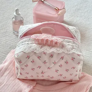 Rosa florale gesteppte Kosmetiktasche mit weißer Borte und Schleifen-Haarklammer für die Reise.