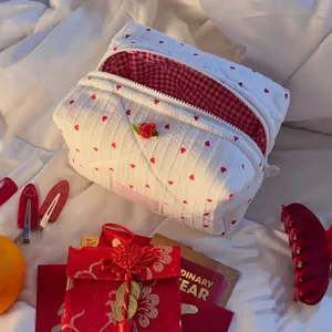Quilted cosmetic bag with red hearts and rose decor, detailed view showing red plaid lining.