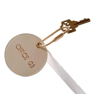 Porte-clés rond minimaliste en laiton sac charm avec étiquette en cuir portable.