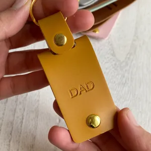 PU leather photo keychain detail showing the embossed DAD text, gold metal snap and ring.