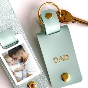 Detail shot of mint green PU leather photo keychain with DAD text and metal keyring.