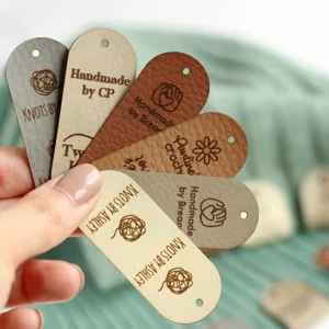 Custom leather tags for handmade crochet knitwear, personalized DIY labels for craft project.