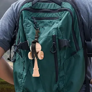 Hölzernes Kendama mit schwarzem Leder-Schutzholster, hängend an einem grünen Rucksack.