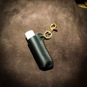 Gedetailleerd overzicht van zwarte PU lederen lippenbalsem hoes met gouden sleutelhanger.