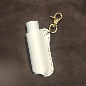Gedetailleerde close-up van witte PU lederen lipbalsem beschermhoes met metalen sleutelhanger.