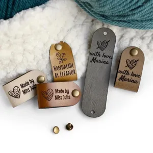 Custom leather labels for handmade knitting, DIY crochet tags with metal rivets and text.