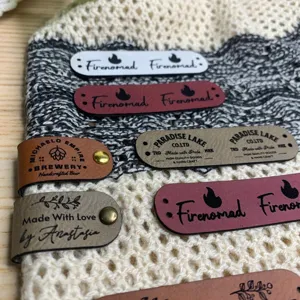 Custom leather tags for handmade crochet knit items featuring metal rivets detail view.
