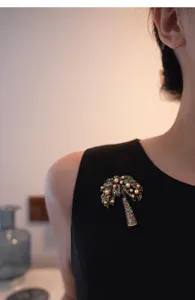Gros plan détaillé d'une broche palmier vintage avec des perles champagne et des cristaux.