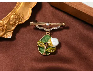 Nahaufnahme Detail der Vintage Goldton Brosche mit grüner Emaillierung und Perle.