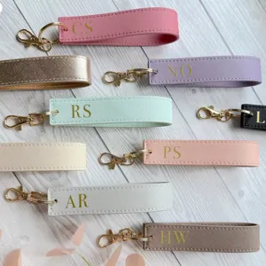 Close-up detail of personalized PU leather wristlet keychain with custom gold initials.
