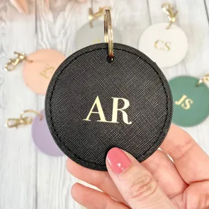 Custom round PU leather keychain with gold initial letters, stylish personalized keyring for gifts.
