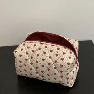 Quilted cosmetic bag detail with red heart pattern, secure zipper closure and practical use.