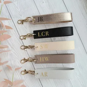 Close up view of PU leather wristlet keychains featuring custom engraved initials.