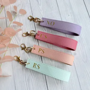 Close-up detail shot of custom personalized PU leather keychains in pastel colors with gold hardware.