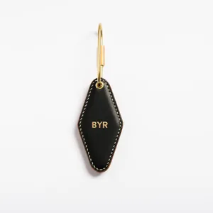 Detail shot of black PU leather diamond shaped keychain with brass keyring and custom letter.