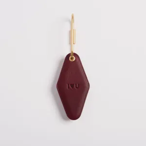 Burgundy PU leather hotel keychain with gold metal ring and debossed design for everyday use.