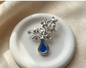 Detailed view of a silver-toned flower vase brooch with blue insert, perfect for traditional wear.
