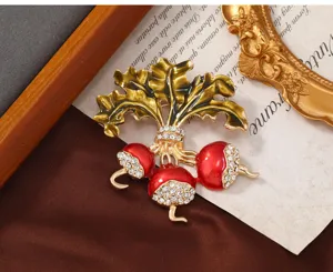 Primer plano de broche de rábano en esmalte rojo con pedrería brillante y detalles dorados.