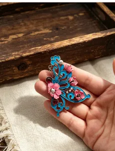 Vue rapprochée de broche papillon en émail style chinois avec fleurs roses pour la tenue.