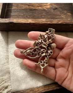 Vue détaillée de l'arrière d'une broche florale en bronze vintage, accessoire.