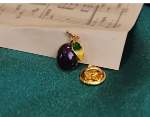 Close-up view of the exquisite enamel fruit brooch featuring purple glaze and gradient leaf design.