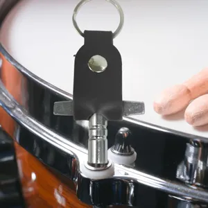 Closeup detail of drum tuning key with black PU leather case and keyring on snare drum.