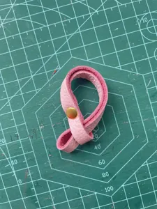 Detail view of pink PU leather bag connector strap with gold metal snap button, ideal accessory.