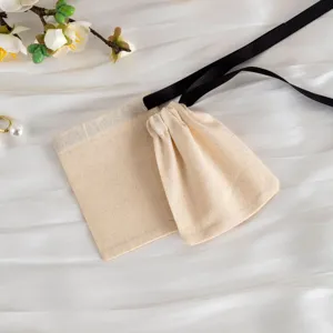 Dettaglio in primo piano di sacchetto gioielli in cotone beige con nastro nero per custodia.